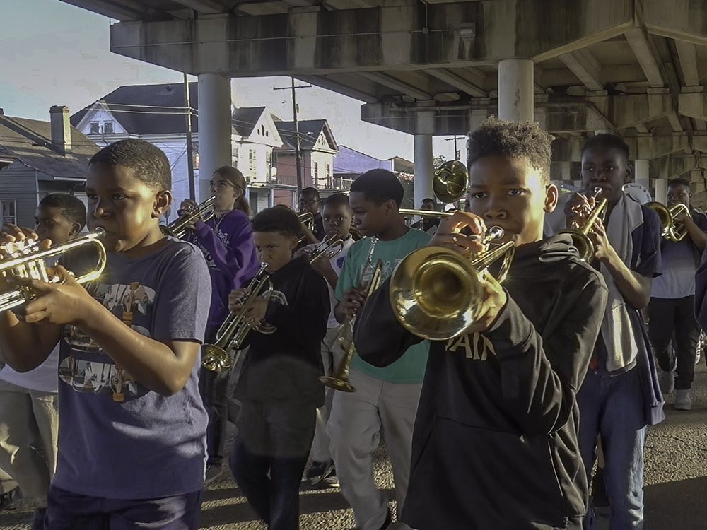 students march in after school parade through city street under overpass