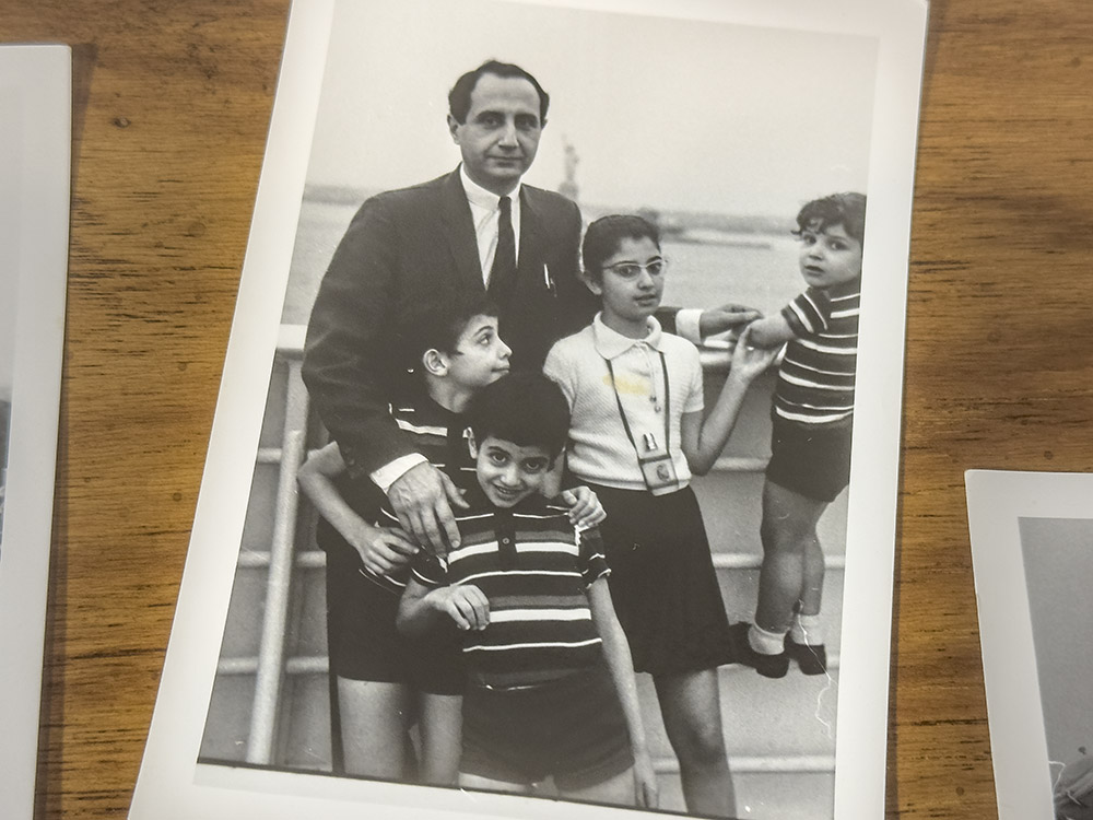 black and white picture of man in dark suit and four children cruising past statue of liberty