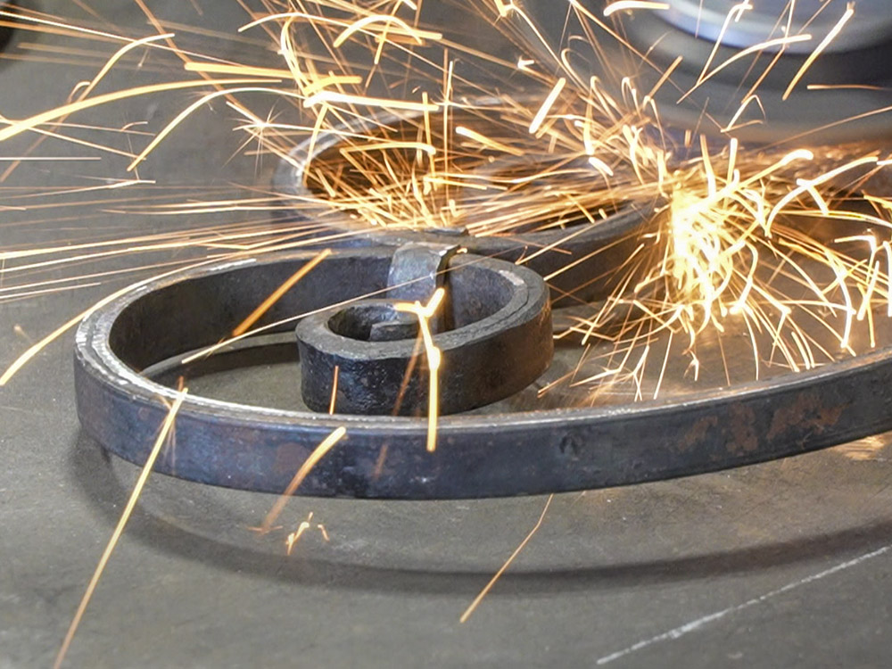 sparks fly from grinder on curved iron piece