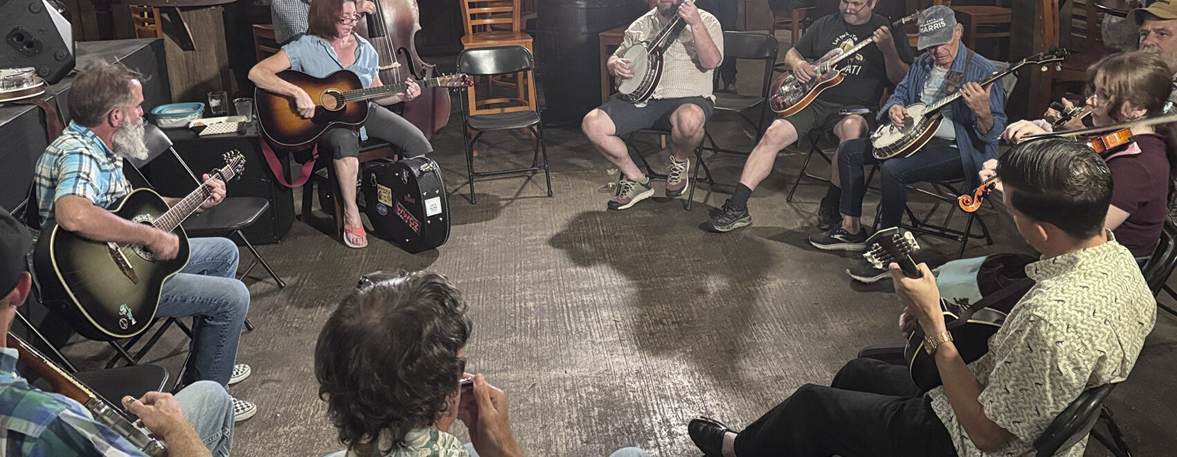 musicians with guitars banjos and fiddles sit in circle for New Orleans jam session
