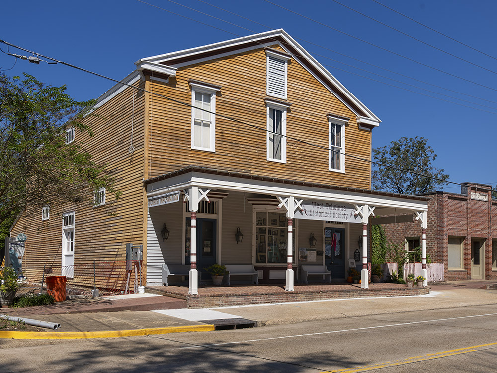 old two story wood building with shaded porch that is now a museum