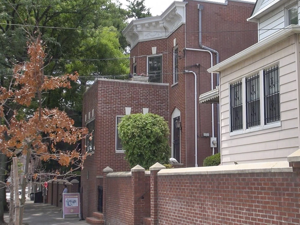 two story red brick home with trees