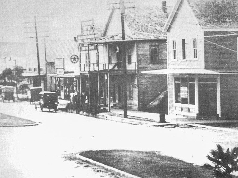 old black and white photo of a small town city street with model t cars