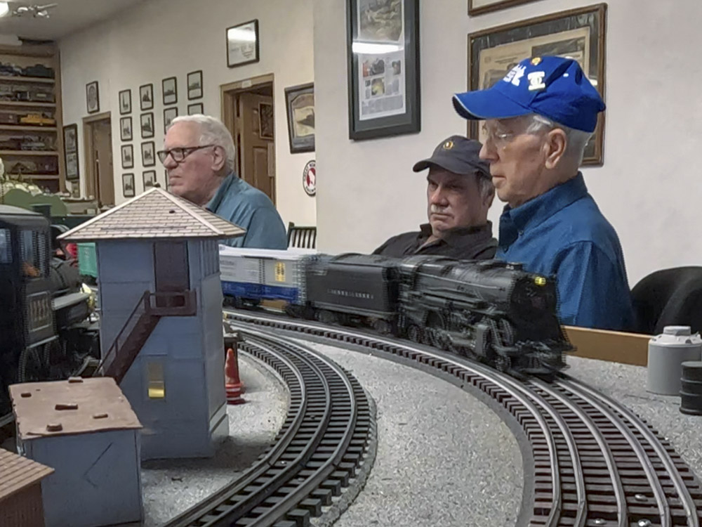 men in blue shirts and caps operate model train