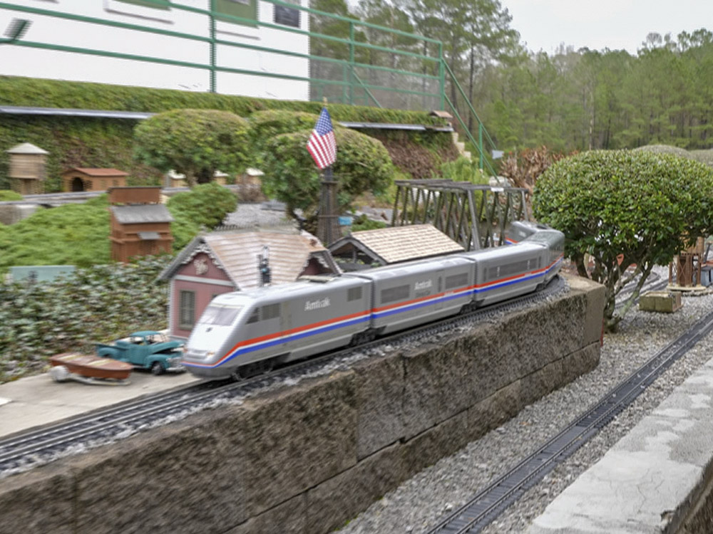amtrak train model on outside track and toy villages