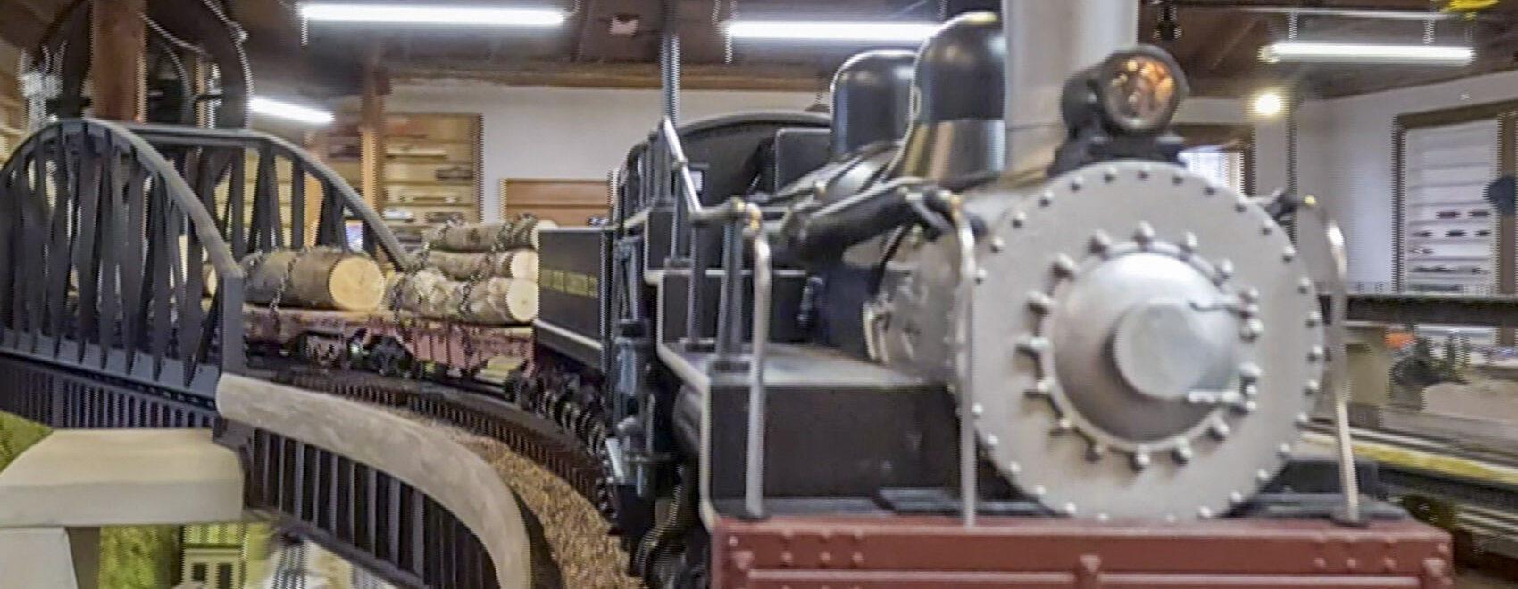 o guage model train engine pulling log cars on track