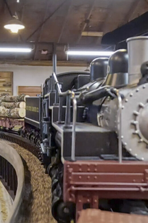 o guage model train engine pulling log cars on track