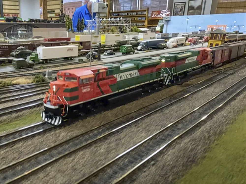 orange and green model train engine in track in rail yard.