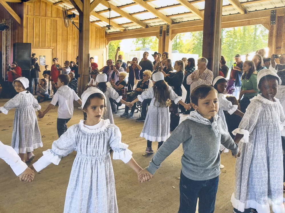 young students dressed in Cajun costumes dancing at a pavillion.