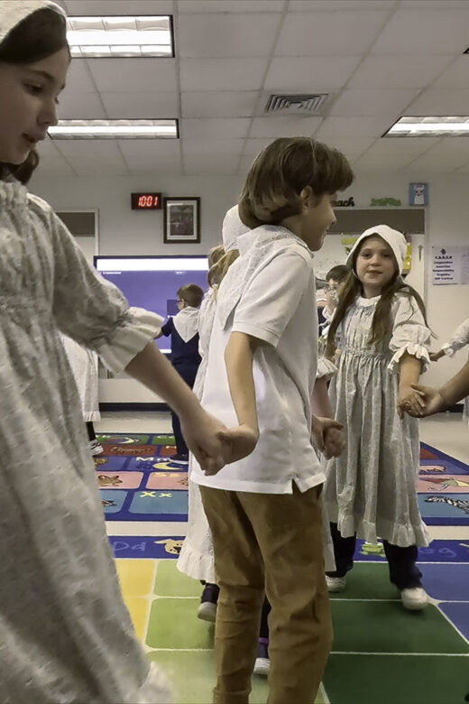 young students holding hands and dancing in traditional Cajun dress