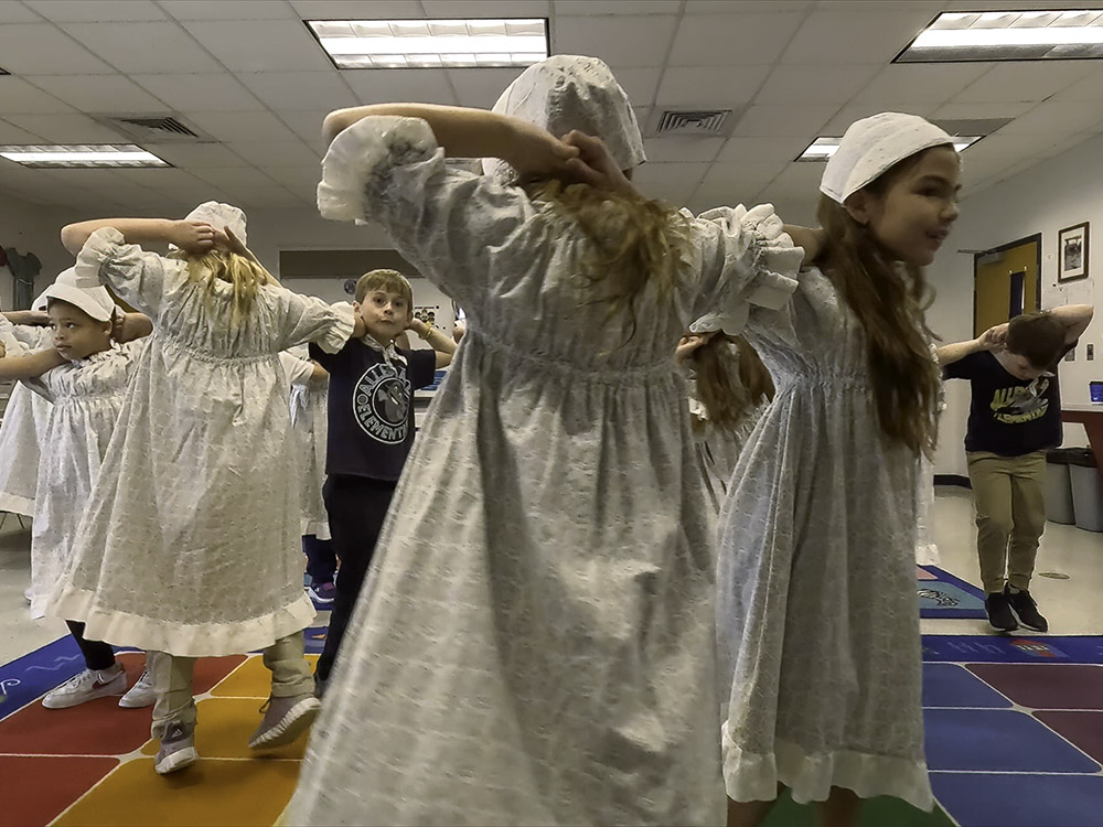 young students dressed in traditiona Cajun costumes dancing