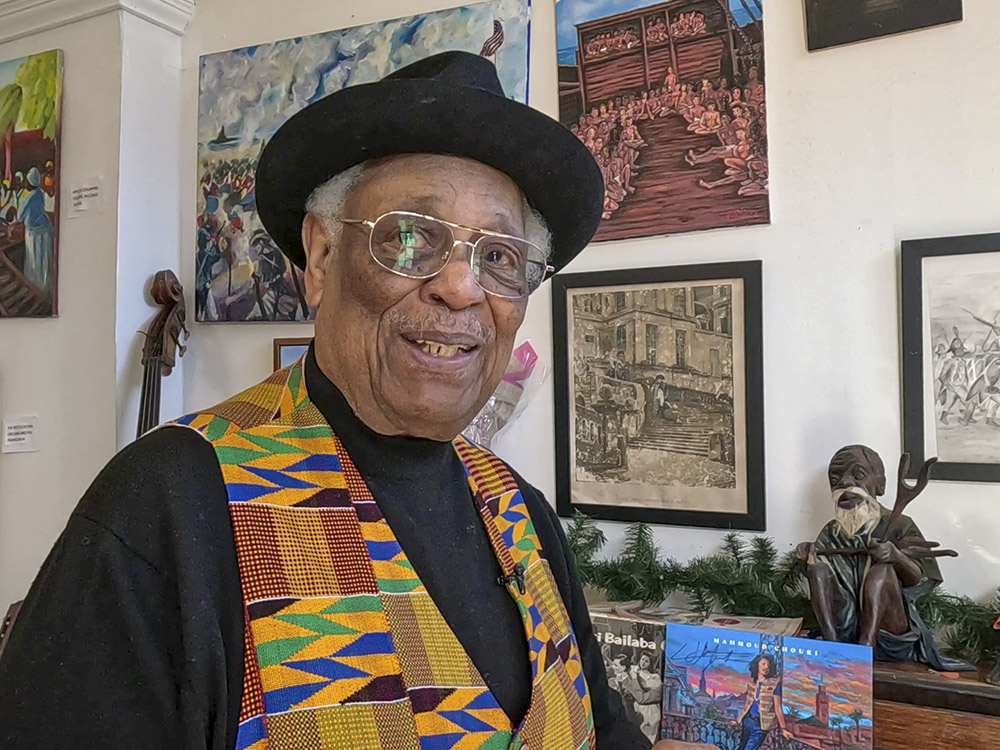 man in black hat and shirt and colorful vest