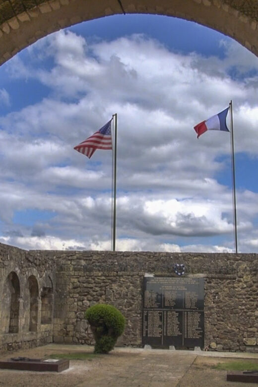american and french flags above a world war 2 memorial