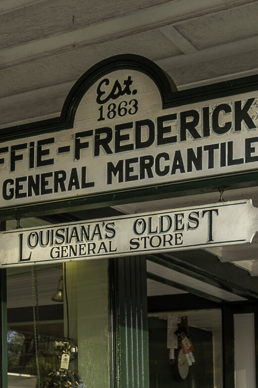 white and green sign hanging under porch for Kaffie-Frederick, Inc General Mercantile Store
