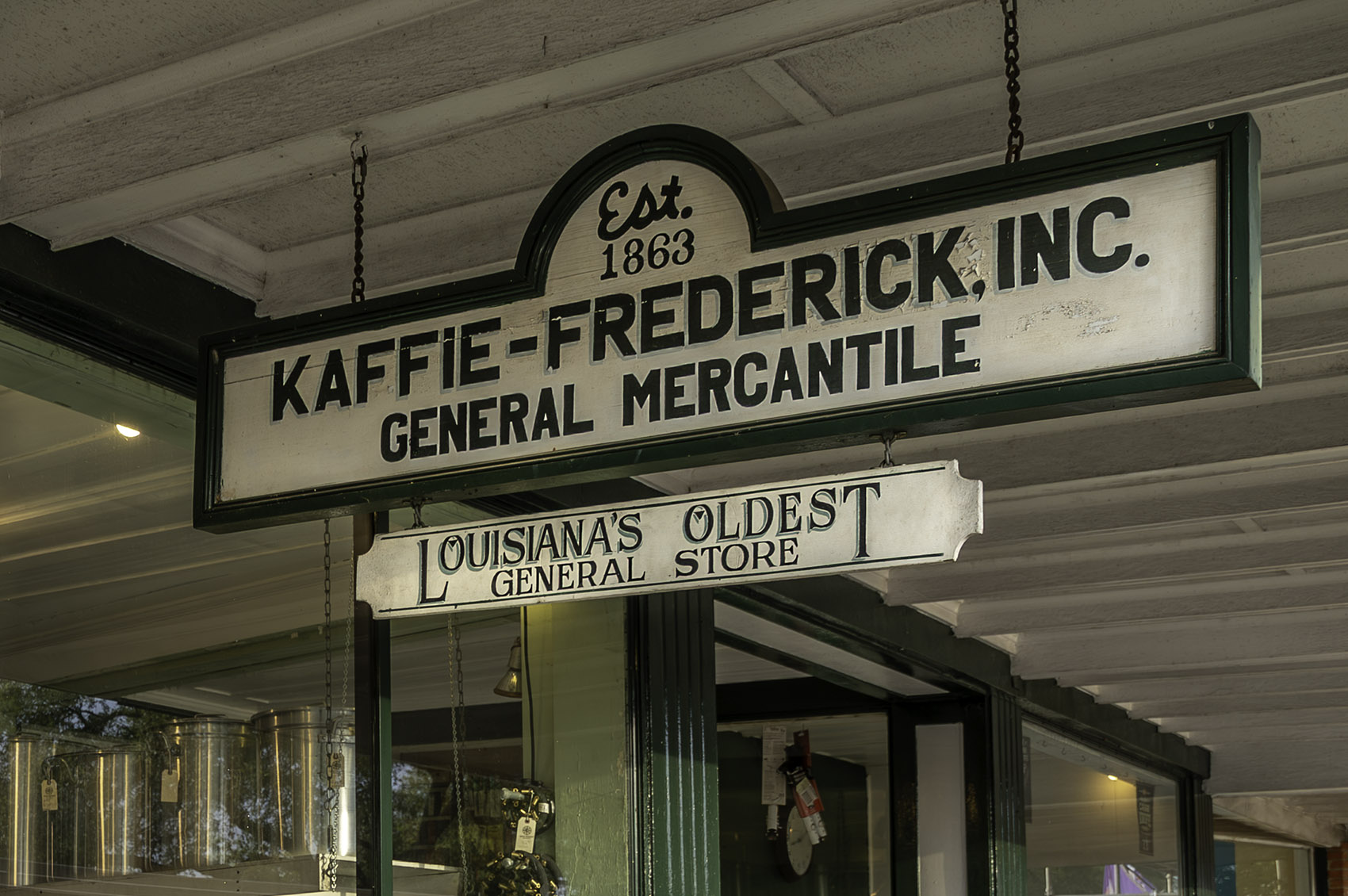 white and green sign hanging under porch for Kaffie-Frederick, Inc General Mercantile Store
