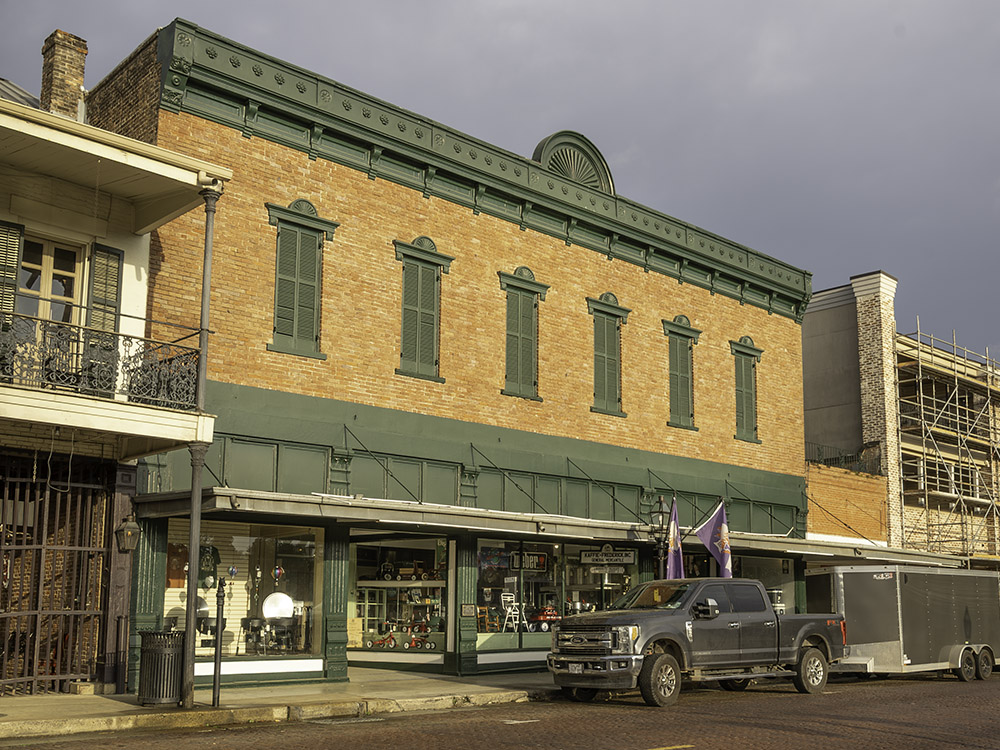 orange brick 2 story building with dark green trim and vehicle parked in front of building.