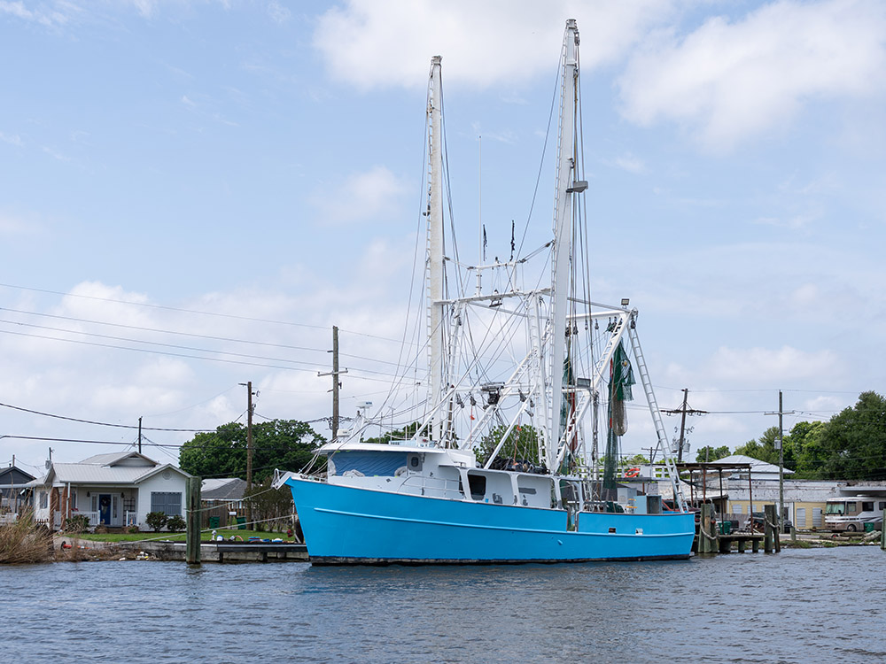 large blue shrimp trawler docked along Louisiana bayou.