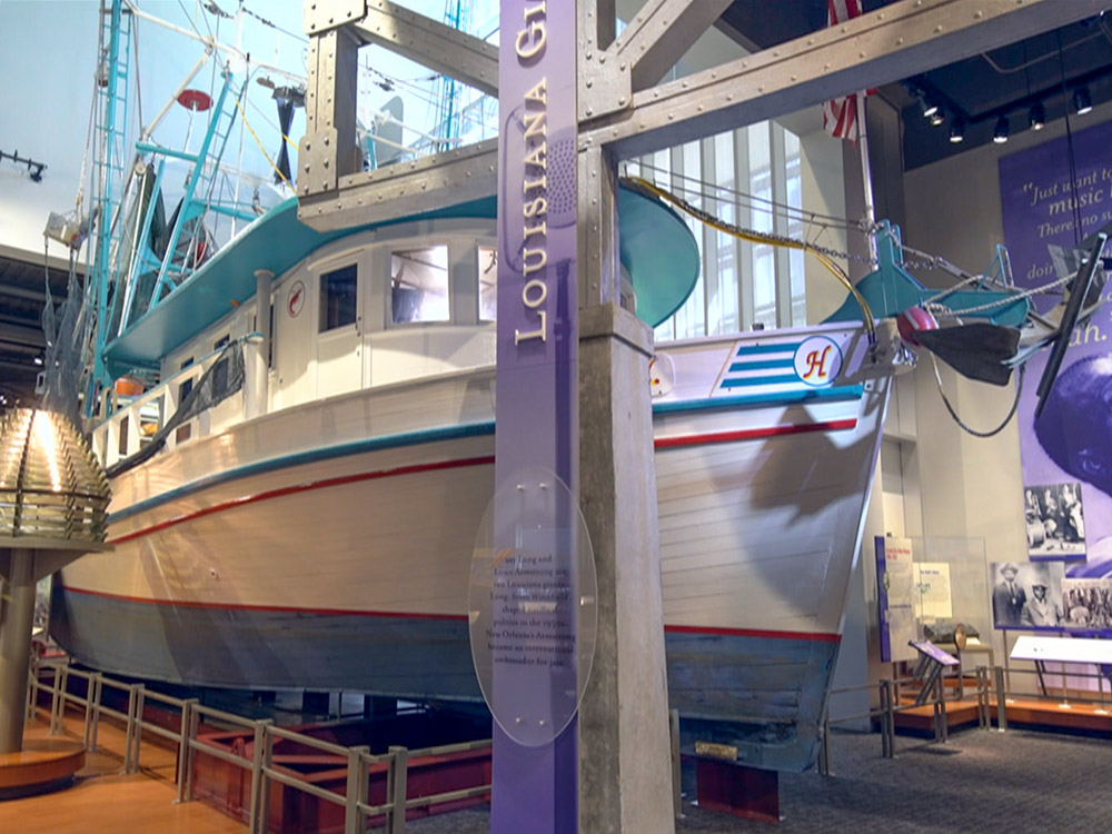 blue and white shrimp trawler on display inside a museum