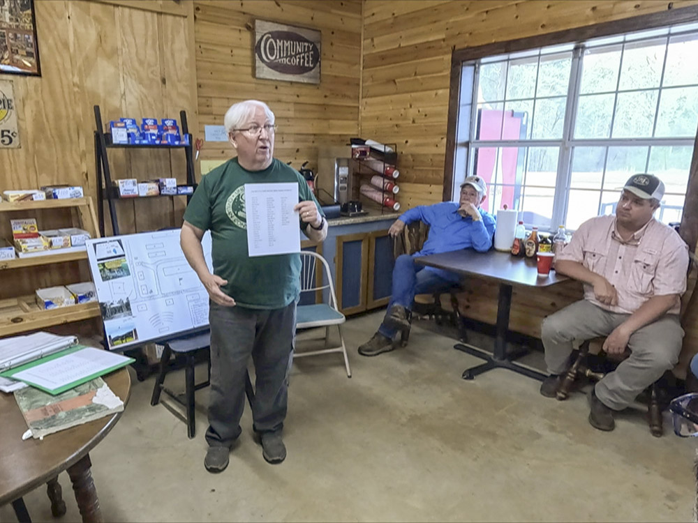 man holding paper addresses small group