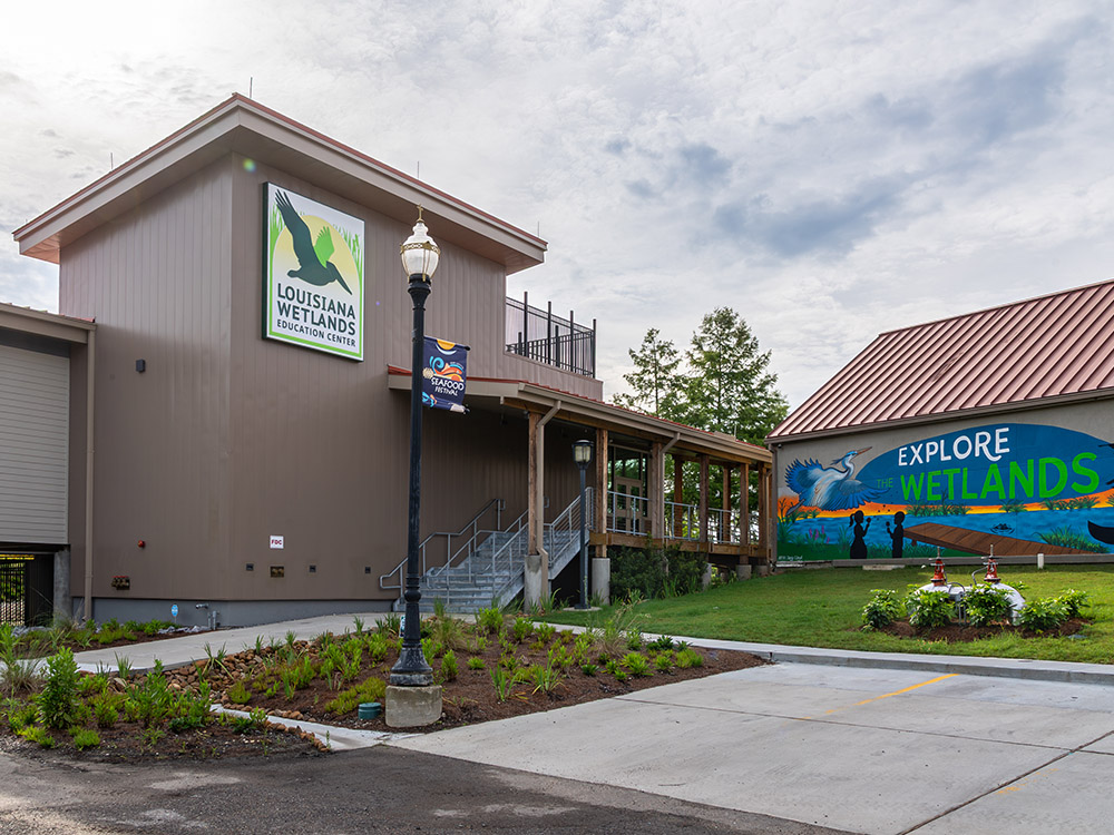 brown square shaped building with sign for Louisiana Wetlands Education Center.