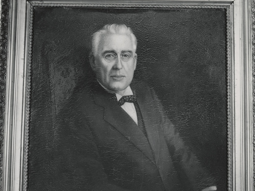 black and white photo of man with gray hair,dark suit and bow tie.