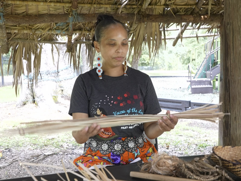 woman with traditional choctaw earrings holding palmetto straw for basket weaving