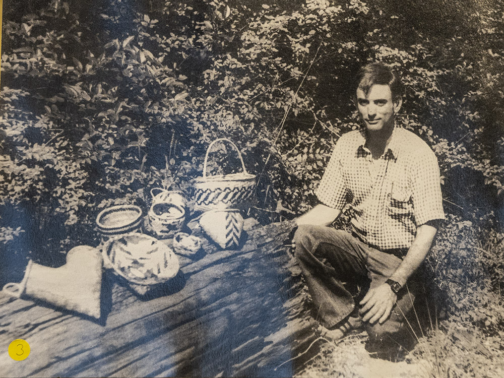 black and white picture of man kneeling next to baskets