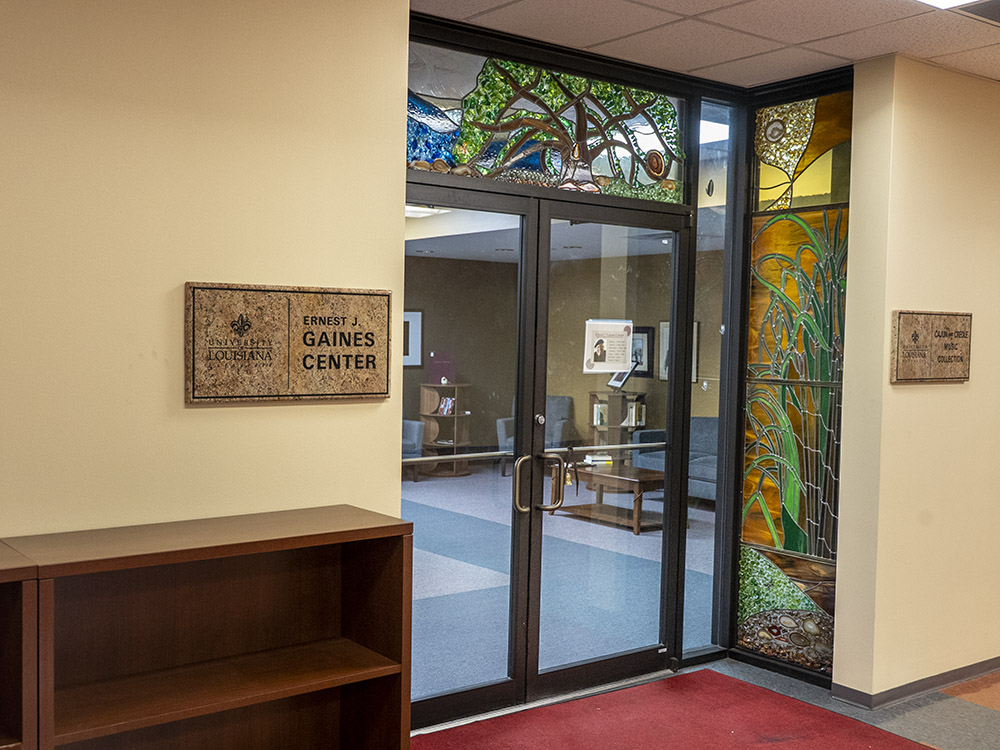 glass doorway framed in stained glass in library with sign ernest gaines center